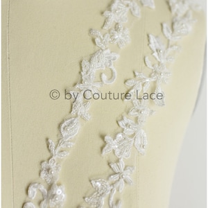 May include: White beaded lace trim with a floral design. The lace is delicate and intricate, with small pearls and sequins.