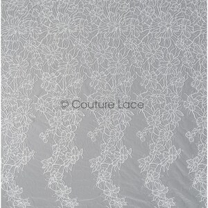 Pu&ograve; includere: Tessuto di pizzo floreale bianco con un design delicato e intricato. Il pizzo presenta un motivo ripetitivo di piccoli fiori e foglie.