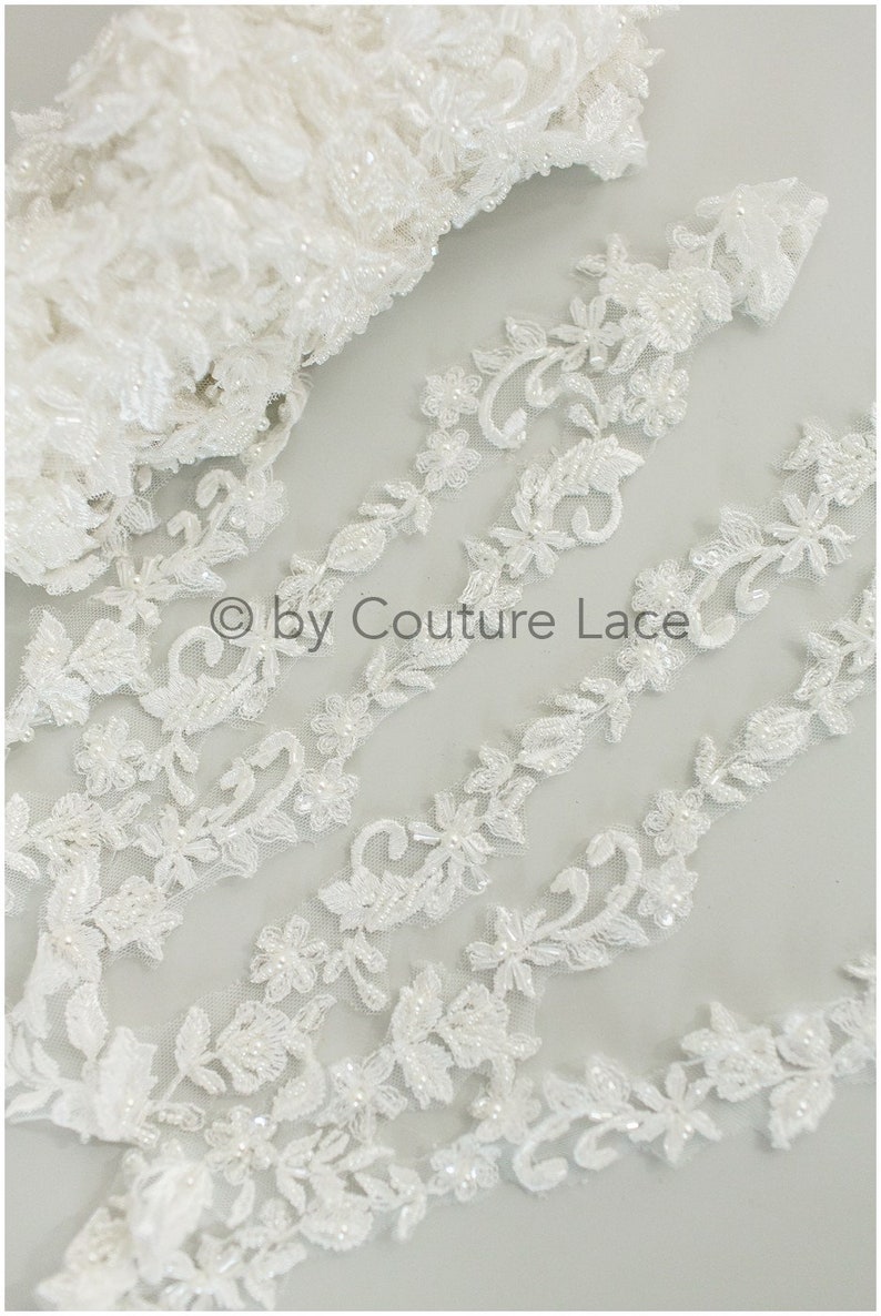 May include: White beaded lace trim with a floral design. The lace is delicate and intricate, with small beads and sequins throughout.  &copy; by Couture Lace
