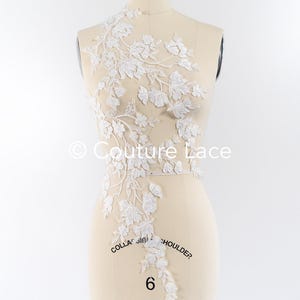 Könnte beinhalten: Weiße florale Spitzenapplikation mit Schmetterlingsdesign. Die Spitze wird auf einer Schaufensterpuppe gezeigt und ist mit "Kragen", "Schulter" und "6" beschriftet.