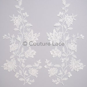 May include: Two white floral lace appliques with delicate floral designs. The appliques are perfect for adding a touch of elegance to any project.