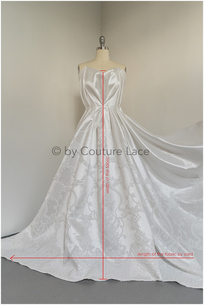 May include: White satin fabric with a damask pattern. The fabric is draped over a dress form and measured for length and width. The text "by Couture Lace" is visible in the image.