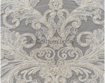 May include: Ivory beaded lace fabric with a floral pattern. The lace features a delicate design with small pearls and intricate details.
