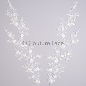 May include: Two white lace appliques with a floral design. The appliques are shaped like branches with small white flowers. The text "Couture Lace" is in the center of the image.