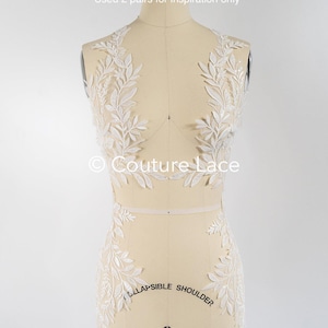 Puede incluir: Aplique de encaje floral blanco para un vestido de novia u otra prenda. El encaje se muestra en un maniquí y presenta un delicado diseño de hojas. "Used 2 pairs for inspiration only" y "Couture Lace" están impresos en la imagen.