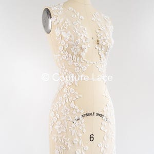 Pode incluir: Aplique de renda floral branca com flores e folhas delicadas. A renda é mostrada em um manequim. "Couture Lace" está escrito no manequim.