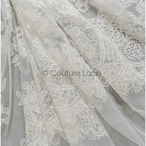 May include: White floral lace fabric with a delicate pattern. The lace is sheer and has a soft, flowing texture.  &copy; Couture Lace