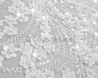 May include: White beaded and sequined fabric with a floral pattern. The fabric is sheer and has a delicate texture.