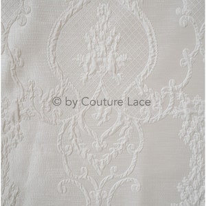 May include: White fabric with an embossed damask pattern. The fabric has a subtle sheen and a soft texture.  &copy; by Couture Lace