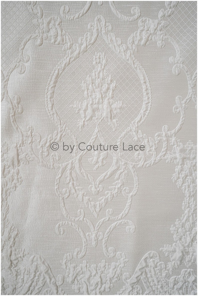 May include: White fabric with an embossed damask pattern. The fabric has a subtle sheen and a soft texture.  &copy; by Couture Lace
