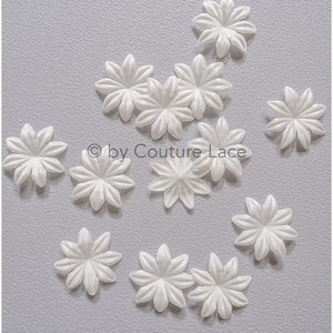 May include: A collection of 12 white satin flower embellishments. The flowers are all the same size and shape, with a five-pointed star design. They are perfect for adding a touch of elegance to any craft project.