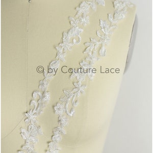 May include: White beaded lace trim with floral designs. The lace is on a white mannequin.