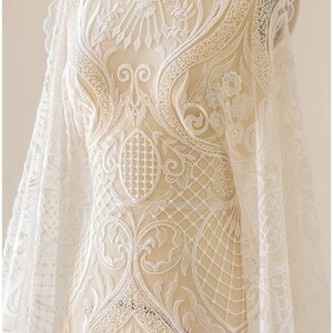 K&ouml;nnte beinhalten: Wei&szlig;er Spitzenstoff mit einem zarten Blumenmuster. Die Spitze hat ein erhabenes Design und ist perfekt, um jedem Projekt einen Hauch von Eleganz zu verleihen.