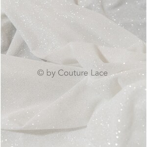 May include: White tulle fabric with a sparkly finish. The fabric is soft and sheer, with a delicate texture. &copy; by Couture Lace