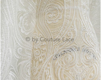 Może przedstawiać: Biała koronka z wzorem paisley i subtelnym połyskiem. Koronka jest delikatna i misterna, o miękkiej, płynnej fakturze. © by Couture Lace