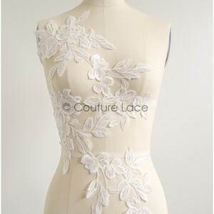 Könnte beinhalten: Weiße florale Spitzenapplikation mit zarten Blättern und Blüten. Die Spitze ist auf einer weißen Schaufensterpuppe gezeigt. Der Text "Couture Lace" ist auf der Spitze sichtbar.