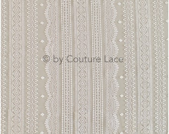 May include: White embroidered lace fabric with a repeating pattern of geometric and floral designs. The fabric has a sheer, delicate texture.