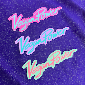 Op de afbeelding: Drie stickers met de tekst "Vegan Power" in verschillende kleuren. De bovenste sticker is roze met lichtblauwe tekst, de middelste sticker is lichtpaars met lichtblauwe tekst en de onderste sticker is lichtgroen met roze tekst.