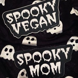 May include: Two black and white stickers with dripping white text. The first sticker says "Spooky Vegan" and the second sticker says "Spooky Mom".