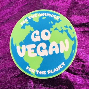 May include: A round sticker with a green and blue earth illustration. The sticker says "For the Animals Go Vegan For the Planet" in white text.