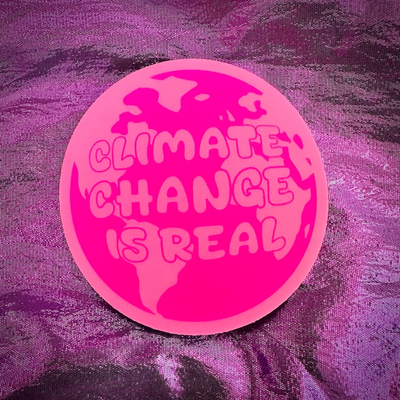 May include: A pink round sticker with a graphic of the Earth and the text "Climate Change Is Real" in a bubble font.