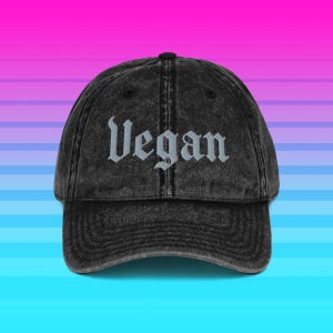 Pode incluir: Boné de beisebol preto desgastado com a palavra "Vegan" bordada em fonte gótica. O boné tem uma aba curva e um design clássico de seis painéis. O fundo é um gradiente de rosa, roxo e azul.