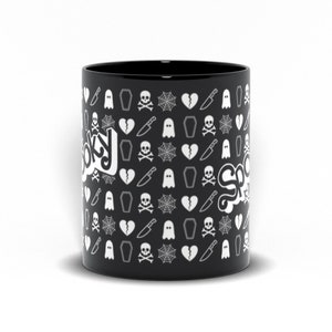 May include: Black ceramic mug with a repeating pattern of white spooky-themed icons, including ghosts, coffins, spiderwebs, and broken hearts. The word "Spooky" is written in white script on the side of the mug.