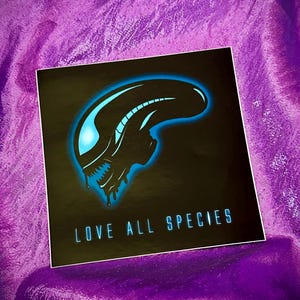 Puede incluir: Una pegatina negra y azul con la silueta de una criatura extraterrestre y el texto "LOVE ALL SPECIES".