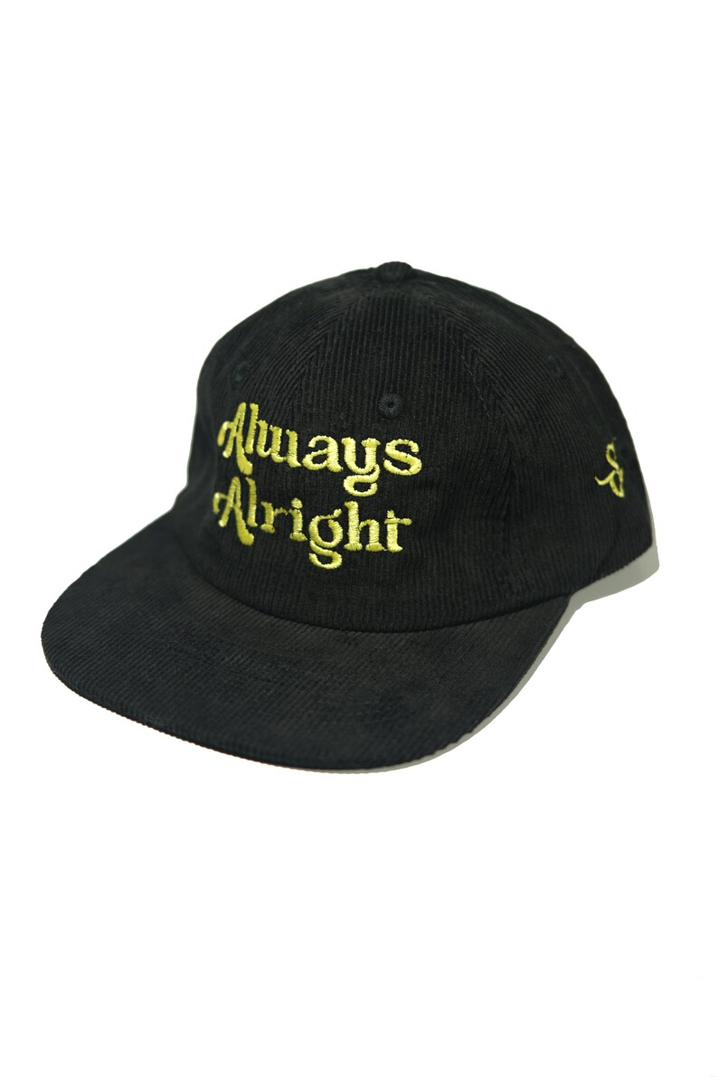 May include: Black corduroy baseball cap with a gold embroidered inscription that reads "Always Alright".
