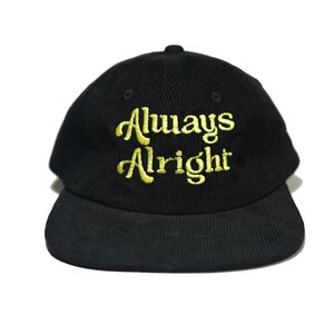 May include: Black corduroy baseball cap with a gold embroidered inscription that reads "Always Alright".