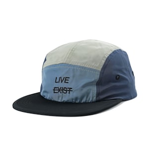 May include: A blue, grey, and black 5-panel cap with a black brim and the text "LIVE EXIST" embroidered on the front.