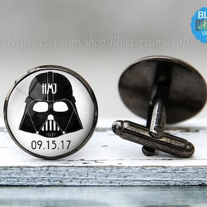 May include: Black and white Darth Vader cufflinks with the initials "HMJ" and the date "09.15.17" on a white background.