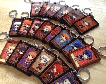 May include: A set of 16 black and gold keychains featuring anime characters with different tarot card designs. Each keychain has a different character and card, including The Fool, The Magician, The Chariot, The Star, and The Emperor.