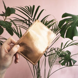 K&ouml;nnte beinhalten: Eine ros&eacute;goldene Lederb&ouml;rse mit einem gen&auml;hten Rand.