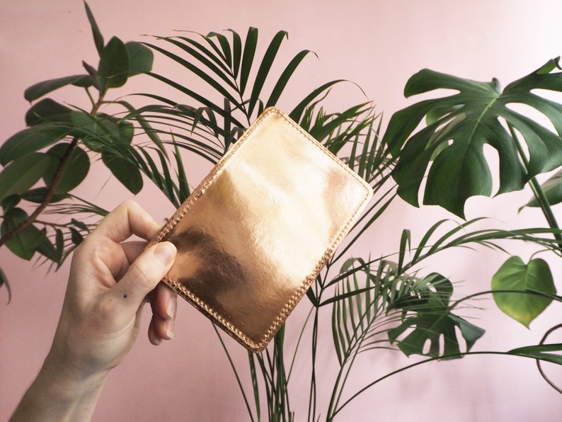 K&ouml;nnte beinhalten: Eine ros&eacute;goldene Lederb&ouml;rse mit einem gen&auml;hten Rand.