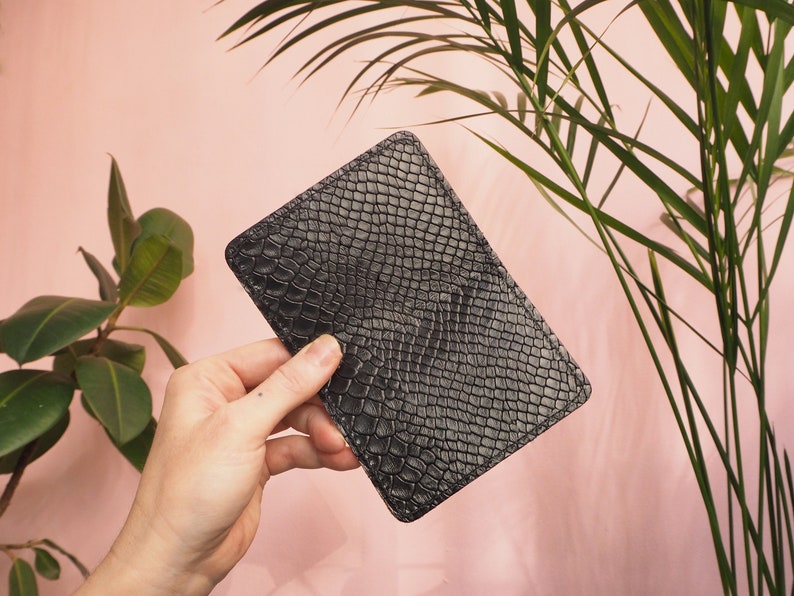 K&ouml;nnte beinhalten: Eine schwarze Lederb&ouml;rse mit Schlangenhautmuster.