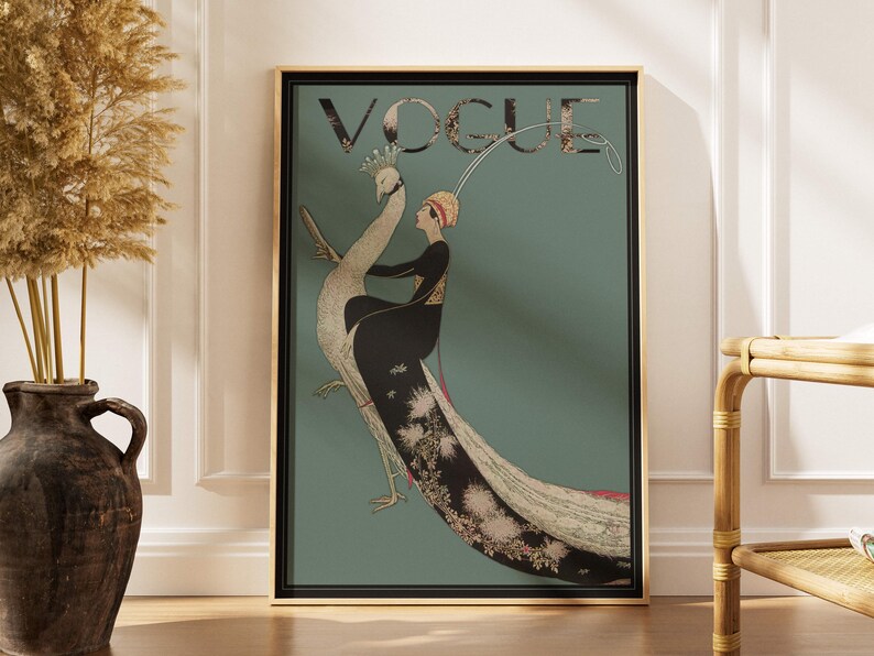 May include: A framed Vogue magazine cover featuring a woman riding a peacock. The artwork has a teal background with the word "VOGUE" at the top. The woman is wearing a black dress and a red hat. The peacock has a long, detailed tail.