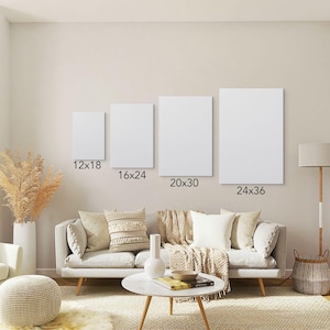May include: Four blank white canvas prints in varying sizes: 12x18, 16x24, 20x30, and 24x36 inches, displayed on a wall above a sofa. The room has a neutral color palette with decorative elements.