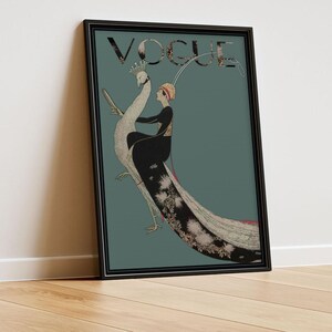 May include: Framed vintage Vogue magazine cover art featuring a woman riding a peacock. The artwork has a teal background with the word "VOGUE" at the top. The woman is wearing a black dress and a hat. The peacock has a long, detailed tail.