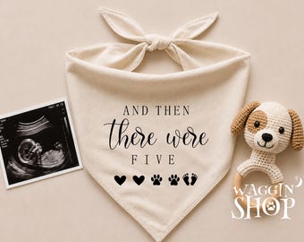 May include: A cream-coloured triangular pet bandana featuring the black text "AND THEN there were FIVE" followed by two heart icons, two paw print icons, and two baby footprint icons. An ultrasound image and a crocheted puppy toy are nearby.