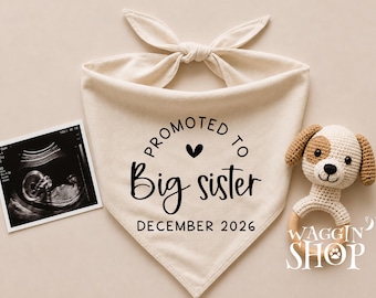 May include: A cream-colored pet bandana with a tie top, featuring the black text PROMOTED TO Big sister DECEMBER 2026 and a small heart. Beside it is a black and white ultrasound scan and a small crocheted puppy toy with a wooden ring handle.