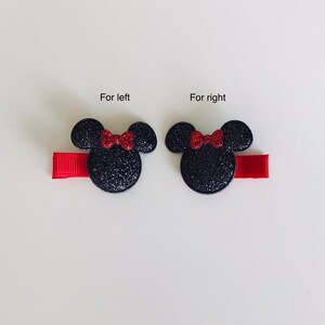 May include: Two black glitter Minnie Mouse hair clips with red bows. The clips are attached to red ribbon.