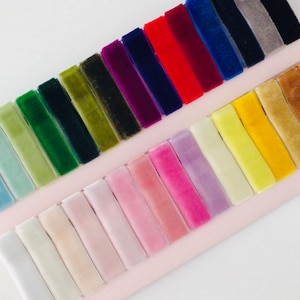 May include: A collection of velvet ribbon samples in a variety of colors, including light blue, green, purple, red, blue, gray, yellow, and brown.