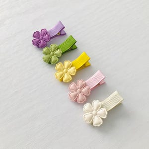 May include: A set of three ceramic mugs with a speckled, matte finish. The mugs are in shades of cream, light brown, and dark brown. Each mug has a simple, minimalist design and a rounded handle.