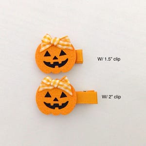 Puede incluir: Dos pinzas para el pelo de fieltro naranja con forma de calabaza, con caras negras talladas y lazos de cuadros amarillos y blancos. Una pinza mide 3,8 cm y la otra 5,1 cm de largo. Perfecto para Halloween.