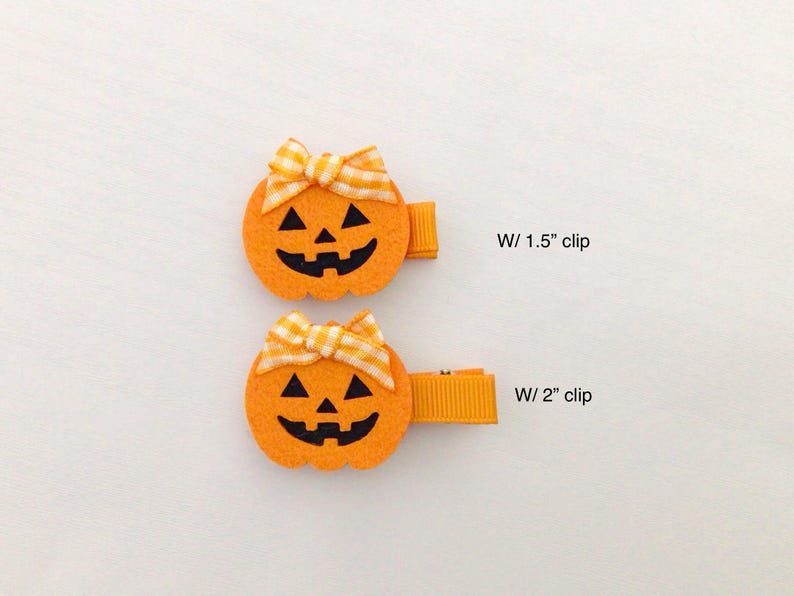 Puede incluir: Dos pinzas para el pelo de fieltro naranja con forma de calabaza, con caras negras talladas y lazos de cuadros amarillos y blancos. Una pinza mide 3,8 cm y la otra 5,1 cm de largo. Perfecto para Halloween.