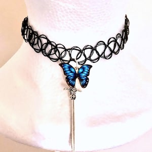 Può includere: Un collare choker nero con un ciondolo a forma di farfalla blu e un ciondolo a forma di spada argentata.
