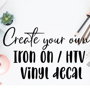 Op de afbeelding: Witte bureau met een laptop, vetplant en briefpapier. De tekst "Create your own IRON ON / HTV VINYL DECAL" is in zwarte letters geschreven. Een roségouden pennenhouder en een smartphone zijn ook zichtbaar.