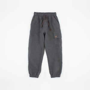 May include: Gray linen cargo pants with a drawstring waist and a buttoned flap pocket on the right leg.