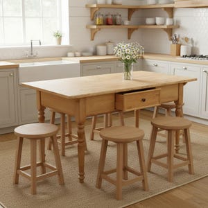 Könnte beinhalten: Helle Kücheninsel aus Holz mit rechteckiger Platte und gedrechselten Beinen. Die Insel hat eine Schublade und ist von vier Holzstühlen umgeben. Eine Vase mit weißen Blumen steht auf der Insel. Die Küche hat hellfarbene Schränke und Regale.